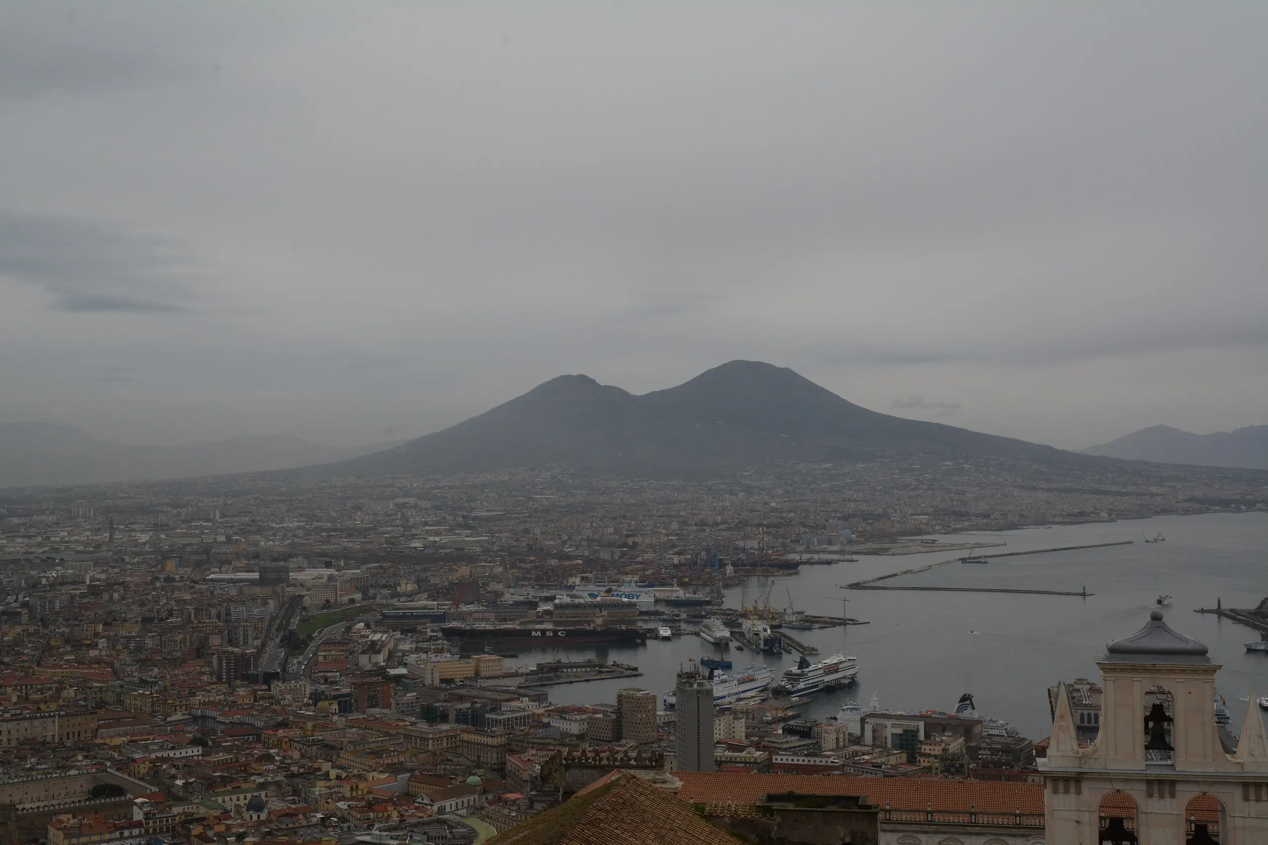 The silhouette of Vesuvius over the bay and rooftops of Naples on a soft grey morning.
